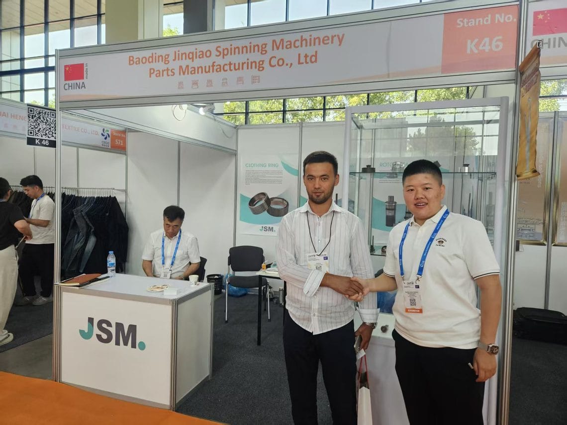 JSM export team shaking hands with a visitor in front of Stand K46 at CAITME 2026 in Tashkent