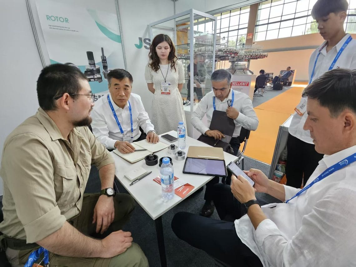 Samples, notebook and tablet on the meeting table during a technical discussion at the JSM stand, CAITME 2026
